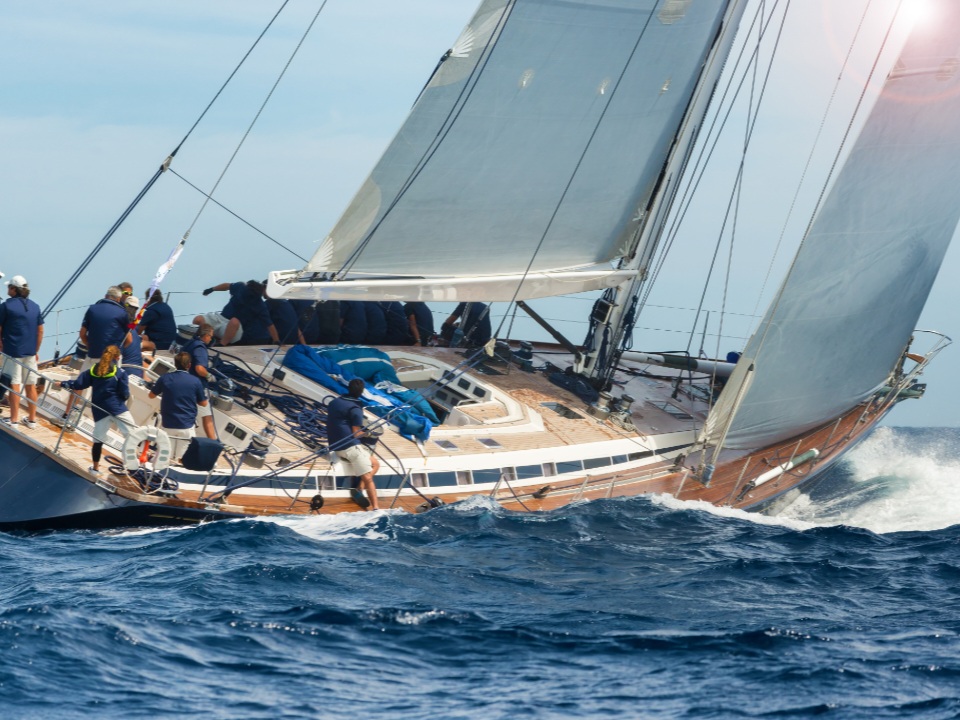 Ein Segelboot auf hoher See mit einem Team, das das Boot gemeinsam steuert.